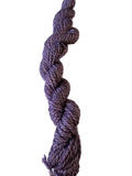 A single twisted skein of heathered purple yarn standing vertically against a plain off-white background.