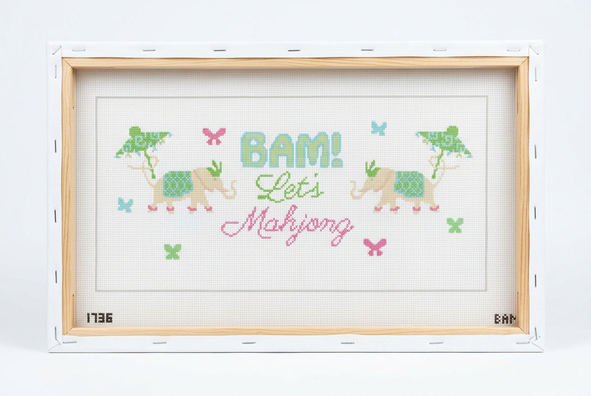 A cross-stitch canvas featuring the text 'BAM! Let's Mahjong' in green and pink lettering, decorated with two beige elephants, butterflies, and crosses on a white mesh fabric. The brand 'Yellow City Cross' is printed along the border.