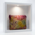 A rectangular pouch or bag with rounded corners, featuring a batik-style floral pattern in yellow, purple, and red tones, shown against a plain white background.