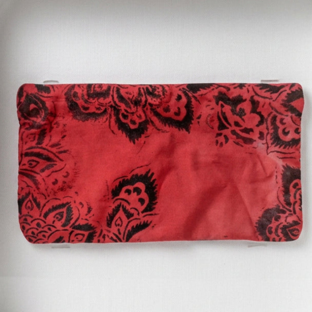 A red fabric pouch with a black floral pattern.