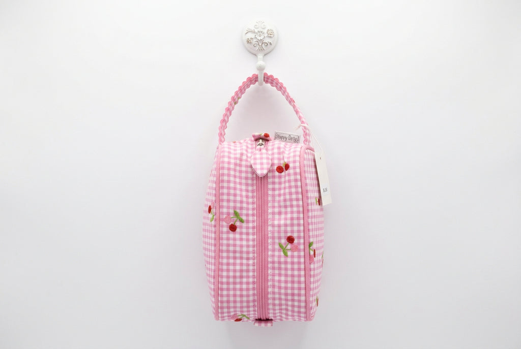 A pink and white gingham zippered pouch with cherry embroidery, featuring a matching pink scalloped strap and a 'Hobby Gift' tag, shown on a white table with a busy background.