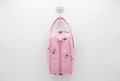 A pink and white gingham zippered pouch with cherry embroidery, featuring a matching pink scalloped strap and a 'Hobby Gift' tag, shown on a white table with a busy background.