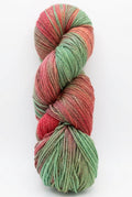A twisted skein of variegated yarn with alternating sections of mint green and dusty rose pink, resting on a dark work surface.