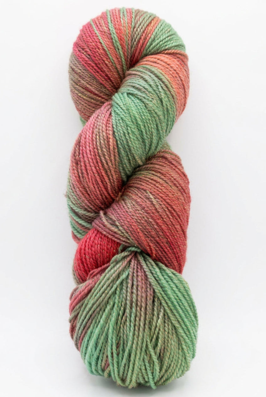 A twisted skein of variegated yarn with alternating sections of mint green and dusty rose pink, resting on a dark work surface.