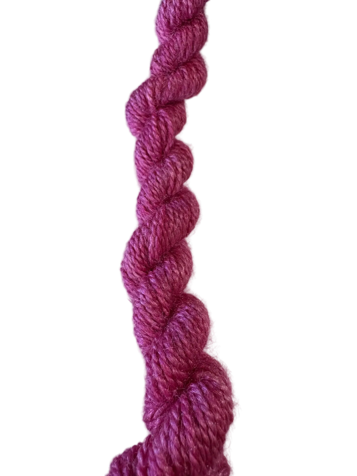 A close-up of a twisted skein of bright magenta pink yarn.