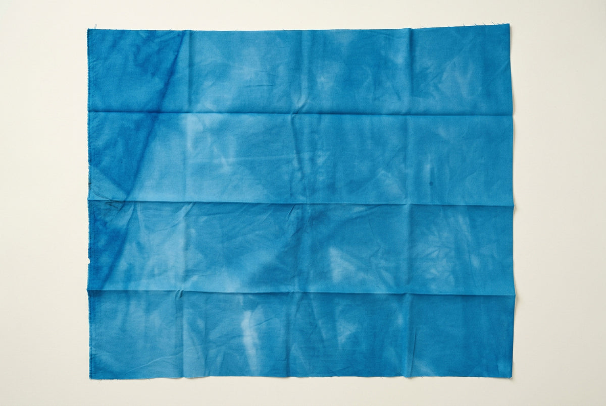 A blue fabric backdrop sheet with visible vertical creases.