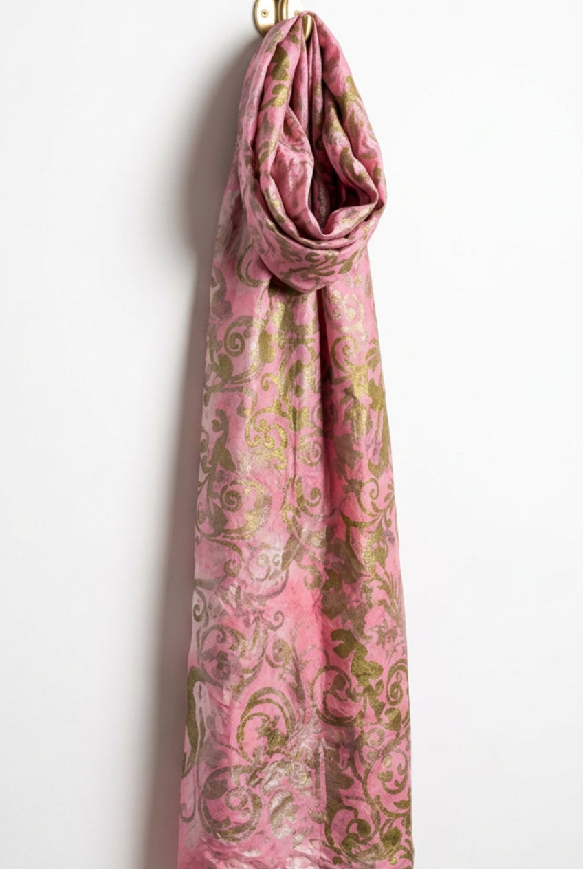 A pink patterned fabric or scarf with a metallic gold damask design.