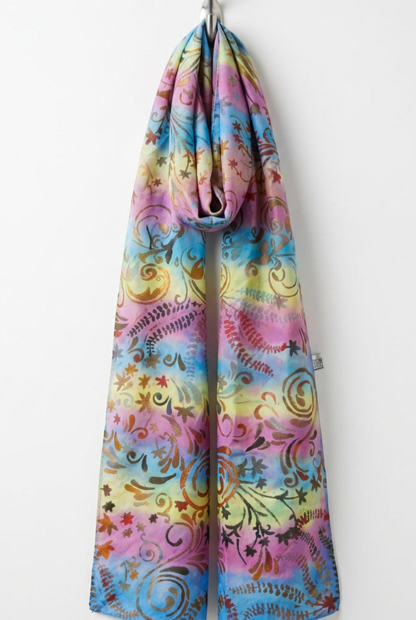 A rectangular fabric panel with a colorful tie-dye pattern in pink, blue, yellow, and purple, decorated with brown and gold swirls and floral motifs.
