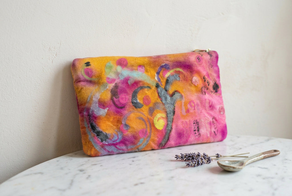 A rectangular abstract art print or textile featuring swirling, fluid brushstrokes in pink, purple, yellow, orange, black, and gray on a white background.