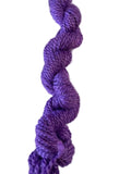 A single twisted hank of purple yarn photographed against a plain white background.
